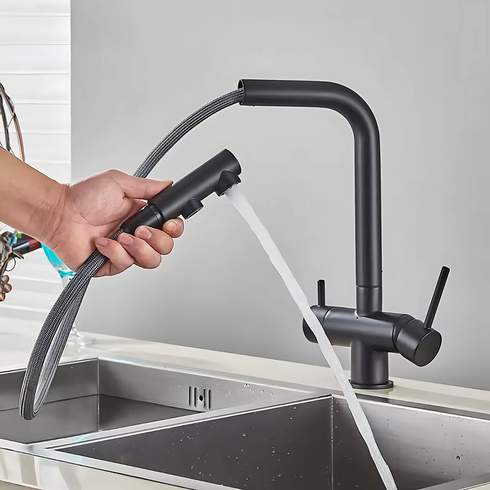 3-Way Pull-Out Black kitchen faucet with handheld spray head being used over a sink.