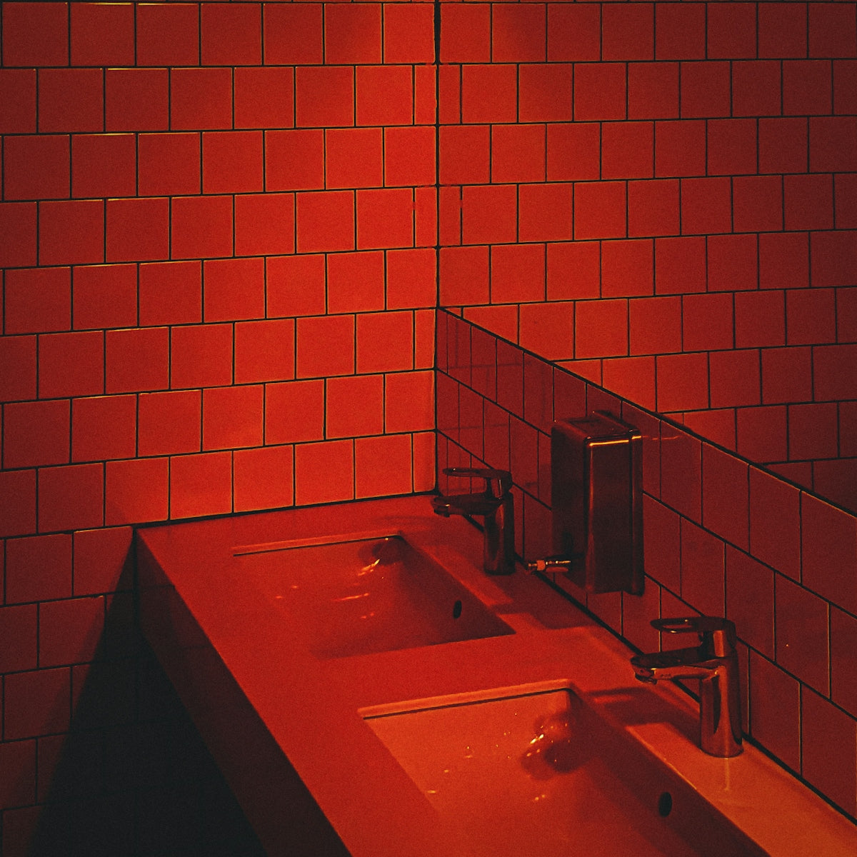 A red bathroom with two sinks and a mirror