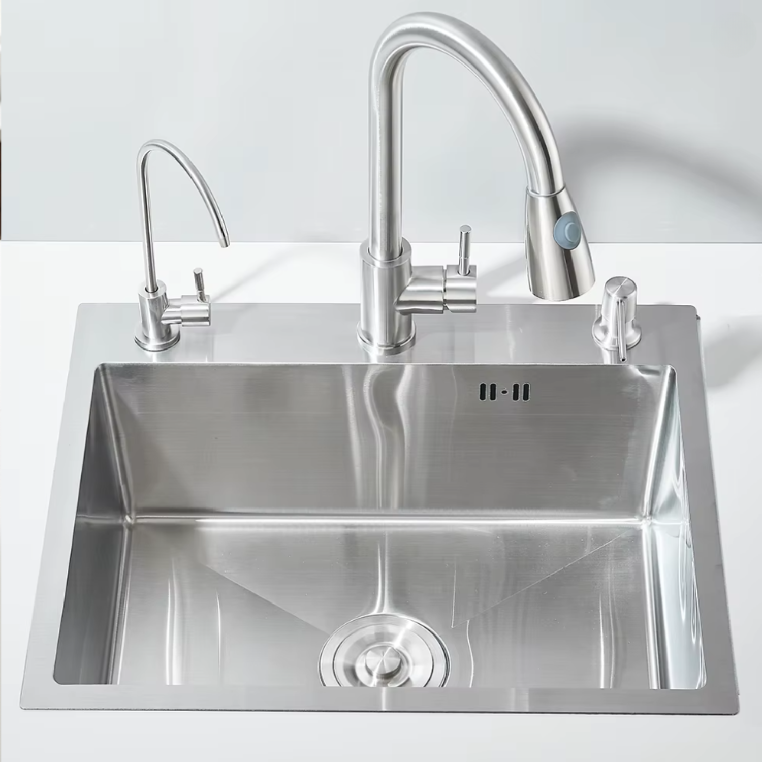Stainless steel kitchen sink with faucet on a white background